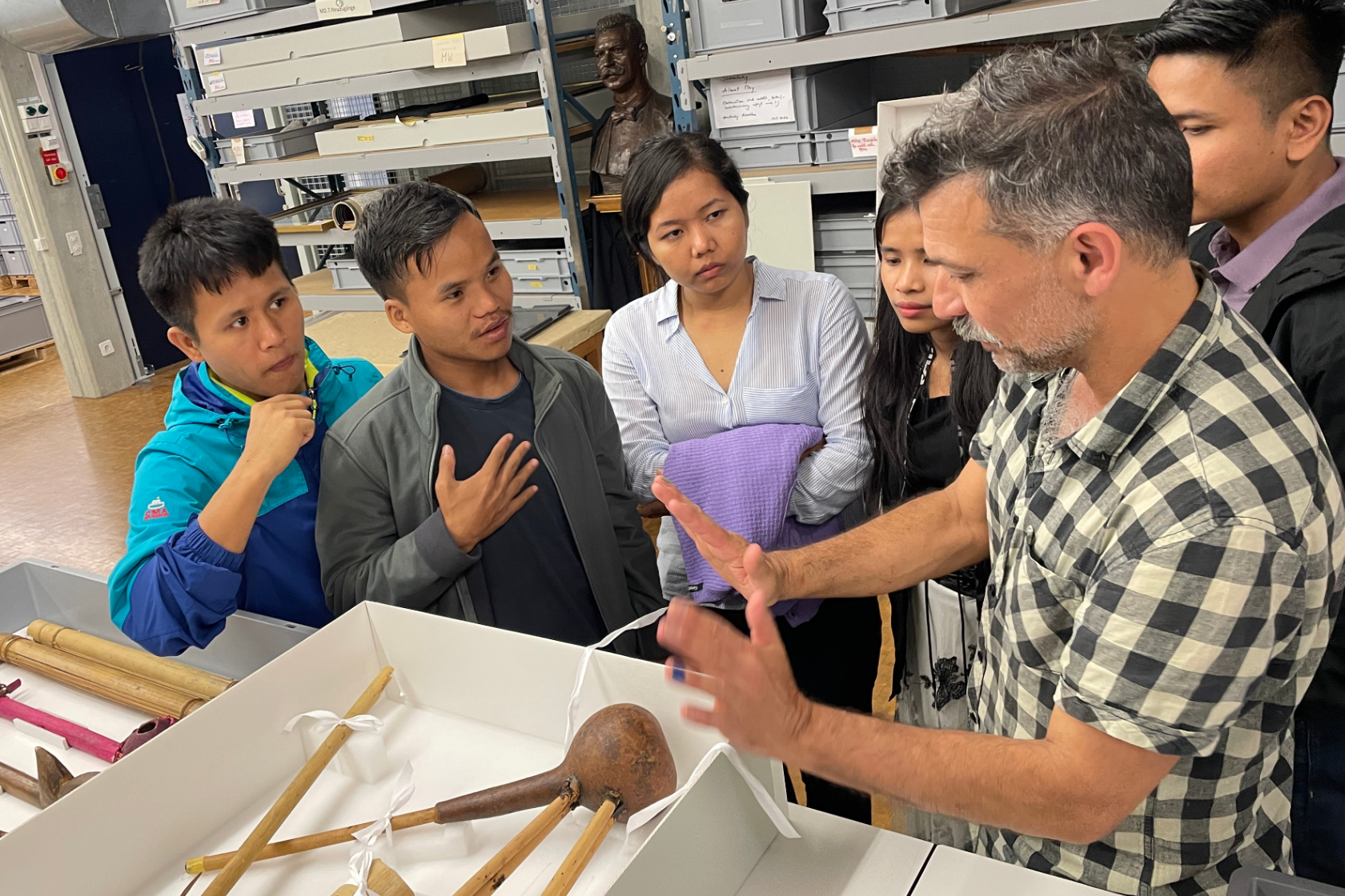 The students from the Chittagong Hill Tracts – Ralong Khumi, Thongpong Mro, Zing Ruat Par Bawm, Zoneikim Pangkhua and U Shamong Kheyang –  discuss with conservator Robert Tobler a gourd pipe in the museum's collection.